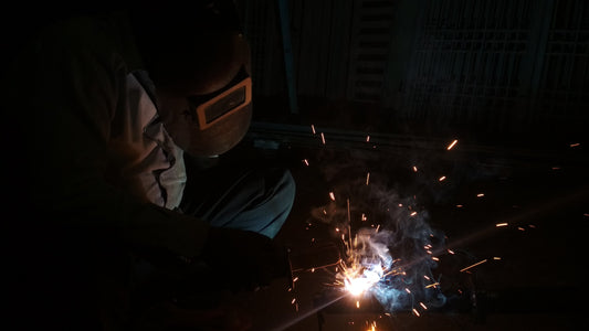 Welder with helmet on welding with sparks flying